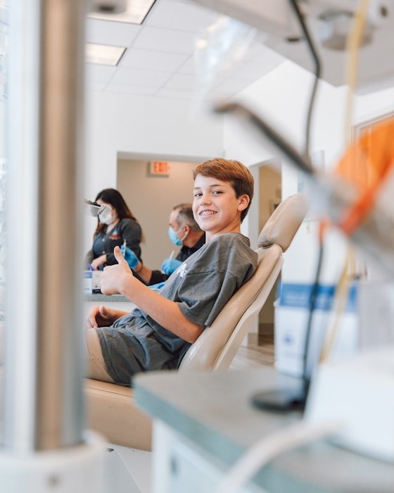 A relaxed young patient giving a thumbs up from a dental chair